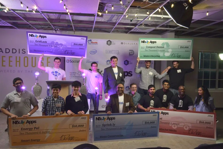 5 groups of individuals at NTx app challenge holding oversized $10,000 checks smiling