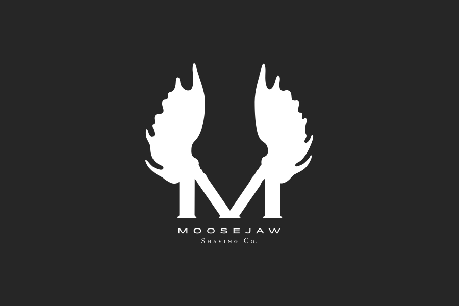 The logo appears on top of a black background. The logo consists of the letter M and mosse antler extending from the top of the letterform. The centered logo and the name Moosejaw Shave Co. are in white.