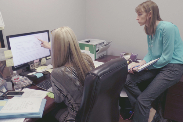 A female paralegal walking a woman through the eFiling process in her office